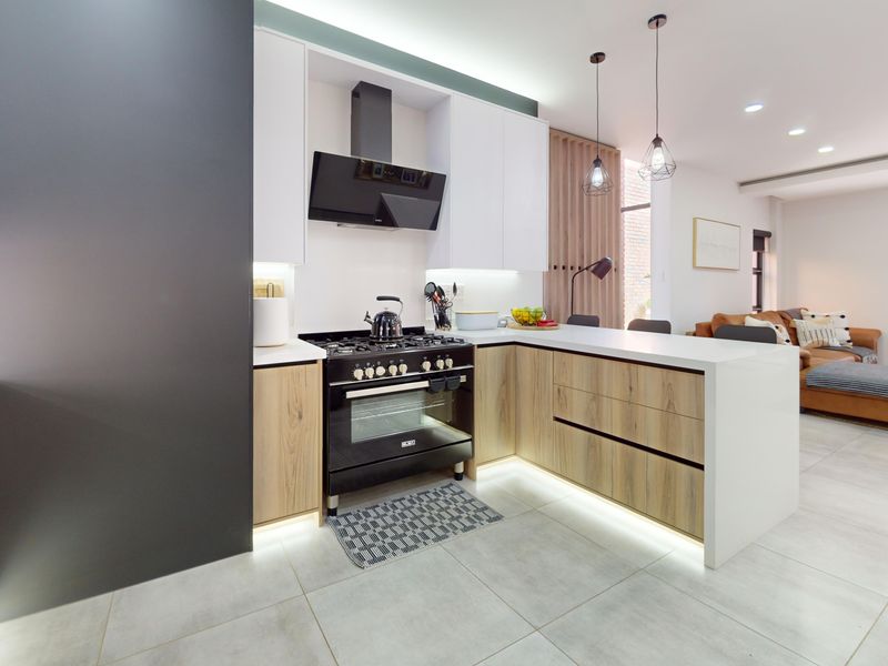Modern open-plan kitchen featuring sleek two-tone cabinetry, stone countertops, integrated gas stove, and stylish pendant lighting, seamlessly flowing into the living area.