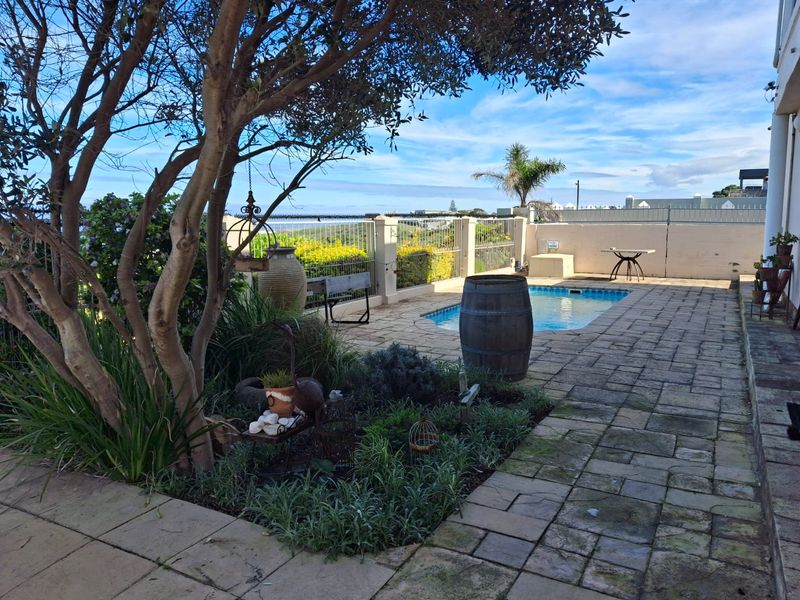 Outdoor pool area featuring a paved patio, landscaped garden, and boundary wall with views, providing a functional space for outdoor relaxation.