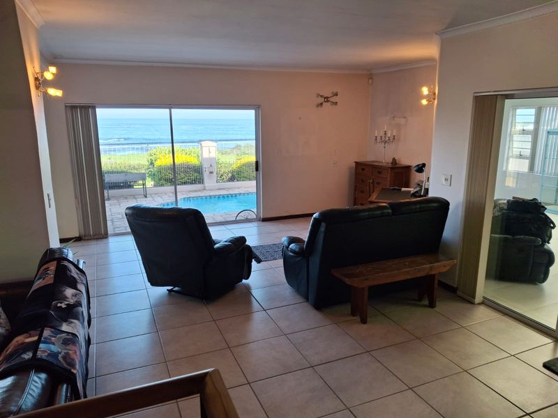 Spacious living room featuring tiled flooring and large sliding glass doors that provide direct access to the pool area and ocean views.