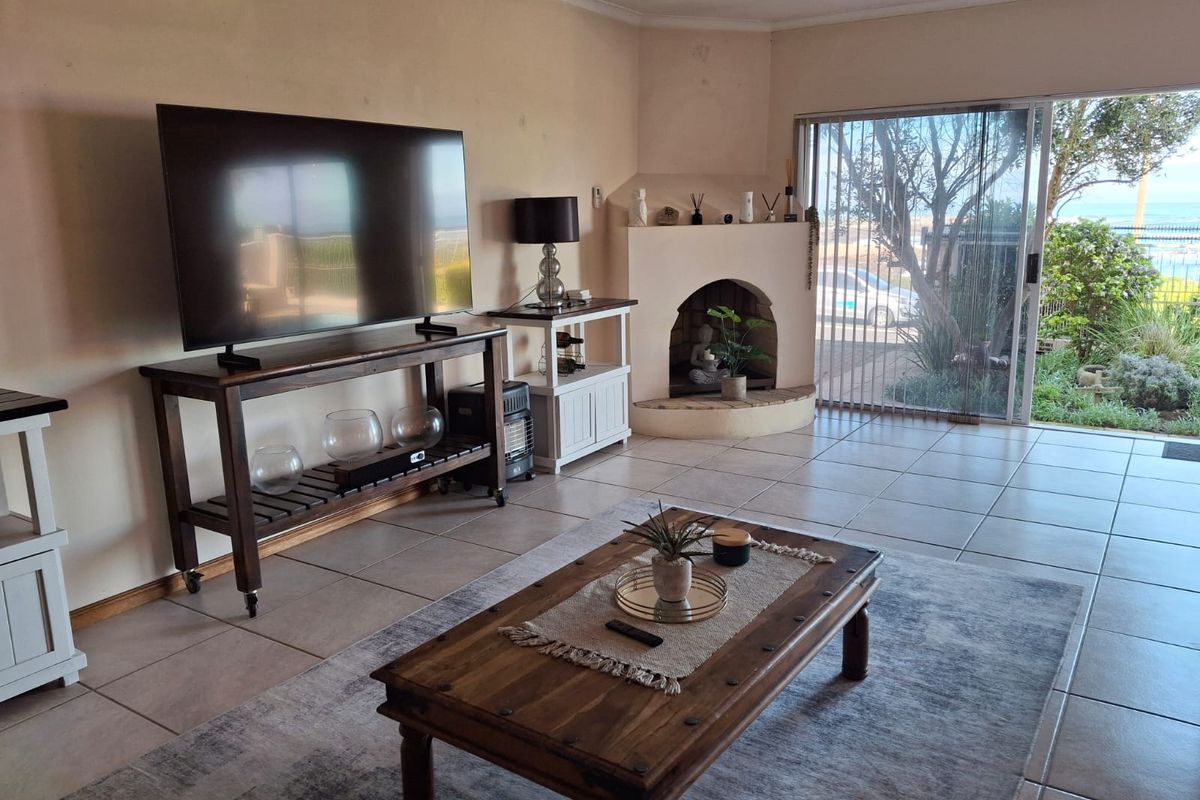 Spacious living room featuring tiled flooring, a built-in fireplace, and large sliding glass doors providing natural light and garden access.
