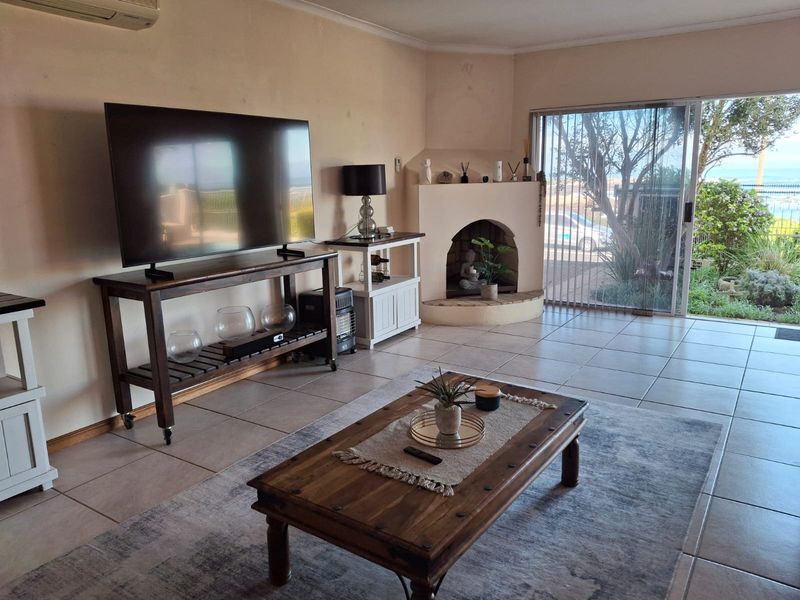 Spacious living room featuring tiled flooring, a built-in fireplace, and large sliding glass doors providing natural light and garden access.