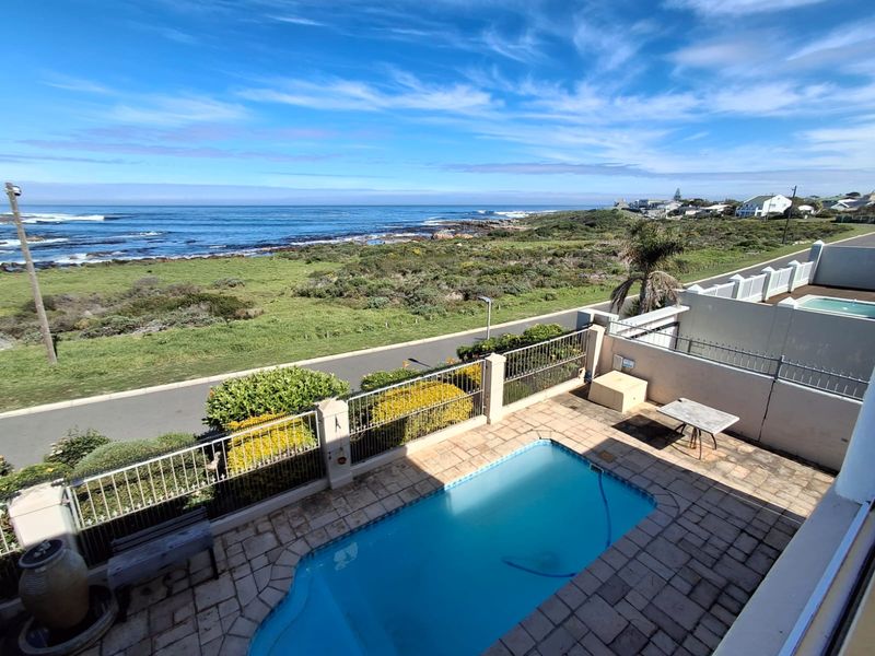 Outdoor pool area featuring a paved deck and metal fencing, offering expansive coastal and ocean views.