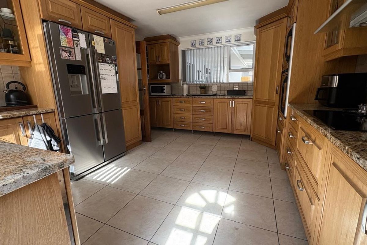 A functional kitchen featuring traditional wooden cabinetry, granite countertops, tiled flooring, and integrated appliances, offering a classic and practical workspace.