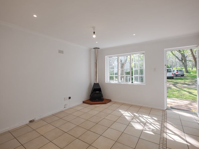 Bright and spacious living area featuring tiled flooring, a freestanding fireplace, and direct access to the garden through a stable door.
