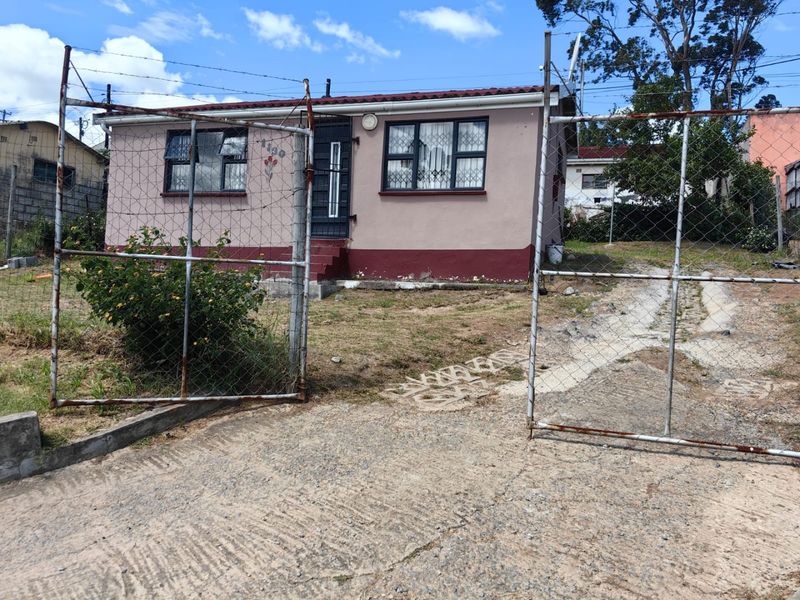 Front view of a detached house featuring a concrete driveway, security fencing, and security bars on the windows.