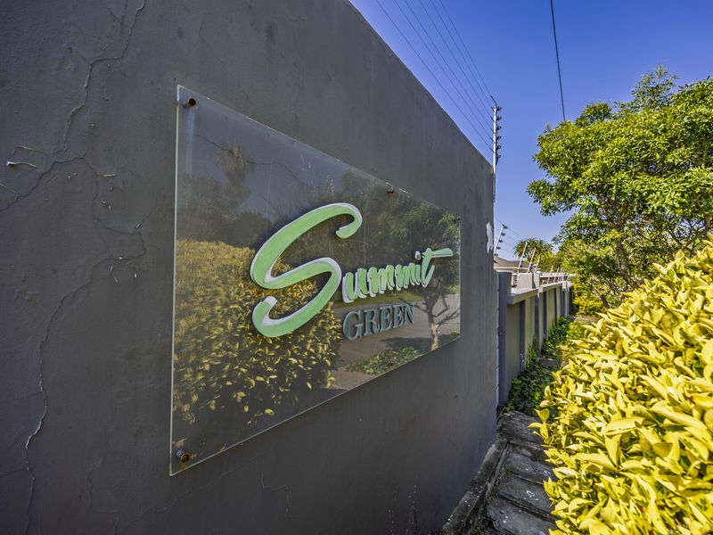 Exterior boundary wall featuring the Summit Green complex signage and integrated electric fencing.