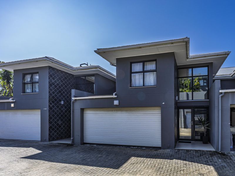 Modern townhouse exterior featuring a double garage, paved driveway, and contemporary dark grey facade with clean architectural lines.