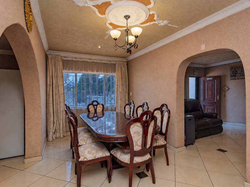 Dining room featuring arched architectural openings, decorative ceiling detailing, and tiled flooring, connecting to adjacent living spaces.