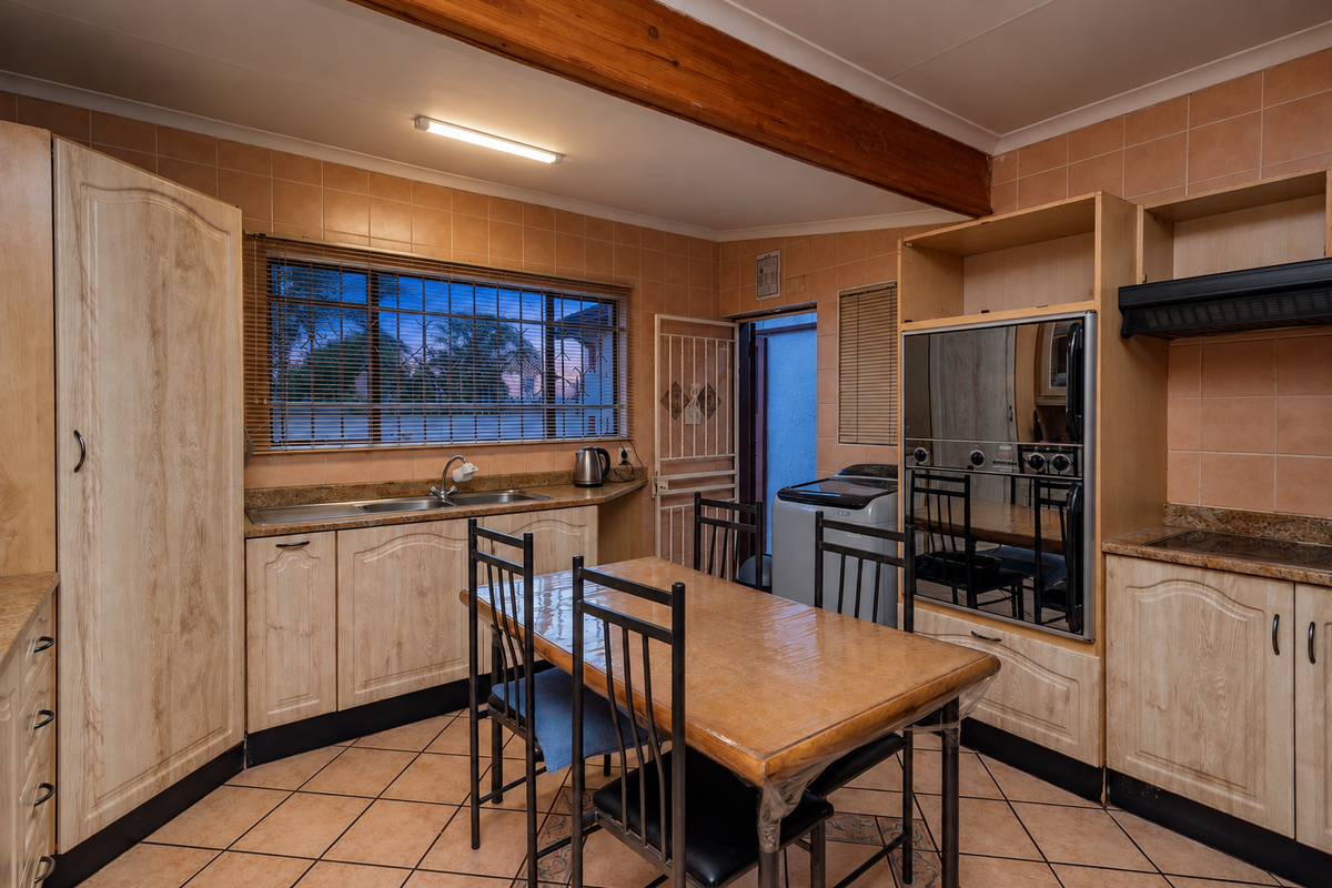 A functional kitchen featuring built-in cabinetry, double sink, integrated oven, and tiled finishes, offering a practical layout with direct access to an outdoor area.