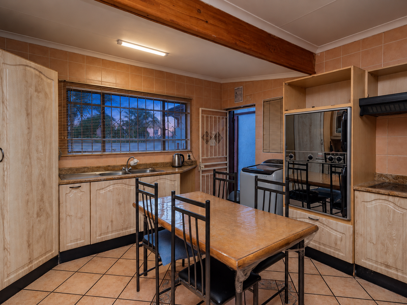 A functional kitchen featuring built-in cabinetry, double sink, integrated oven, and tiled finishes, offering a practical layout with direct access to an outdoor area.