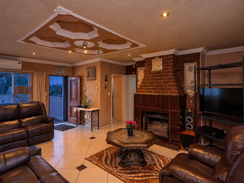 Spacious living room featuring a prominent brick fireplace, decorative ceiling detail, tiled flooring, and direct access to an outdoor balcony area.