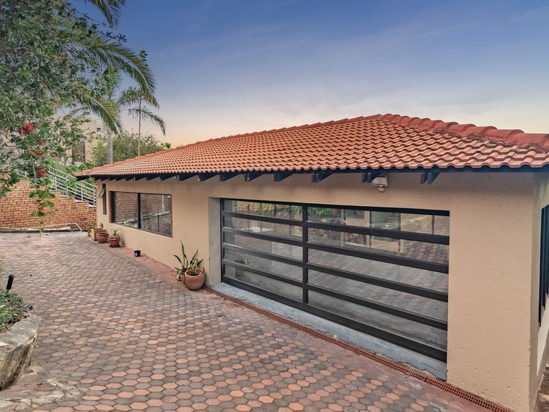 A well-maintained detached garage featuring a modern sectional door, terracotta tiled roof, and a paved driveway area.