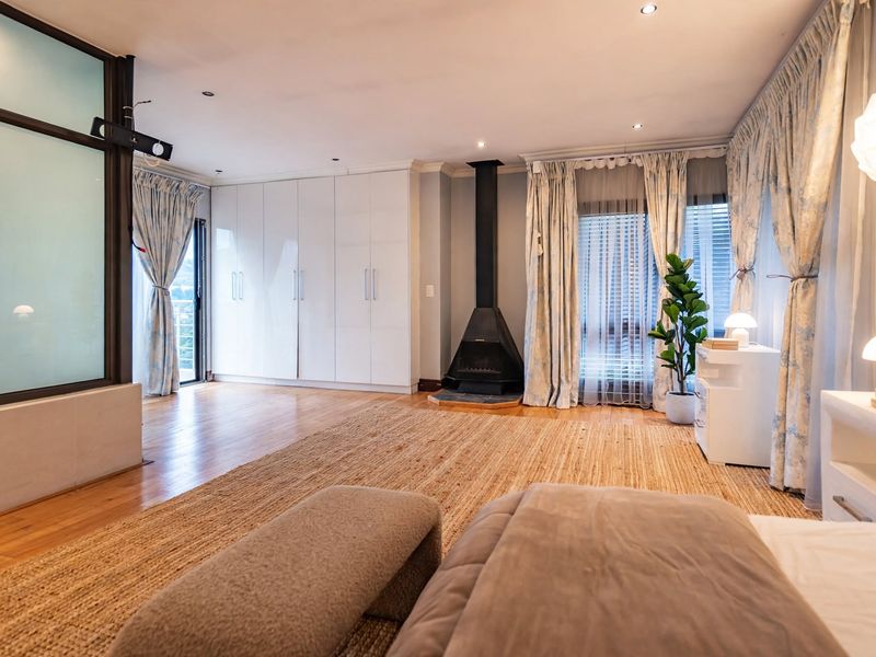Spacious bedroom featuring hardwood flooring, built-in storage cupboards, and a modern freestanding fireplace, with direct access to an outdoor area.
