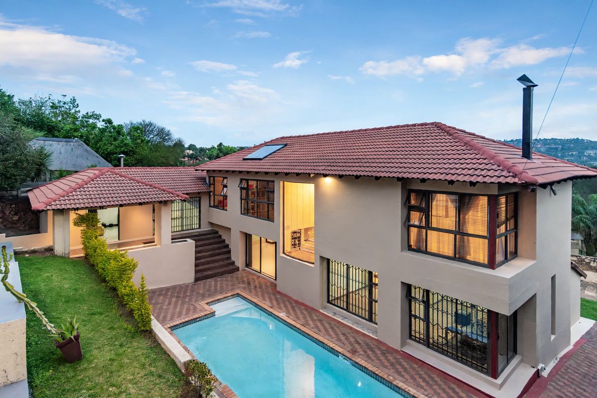 Rear view of a multi-level house featuring a swimming pool, paved patio area, and well-maintained exterior finishes with a tiled roof.