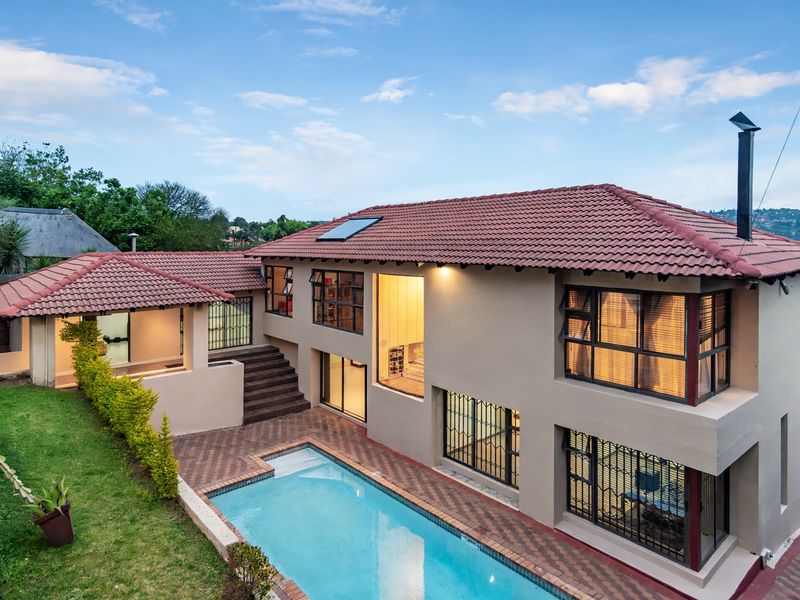 Rear view of a multi-level house featuring a swimming pool, paved patio area, and well-maintained exterior finishes with a tiled roof.