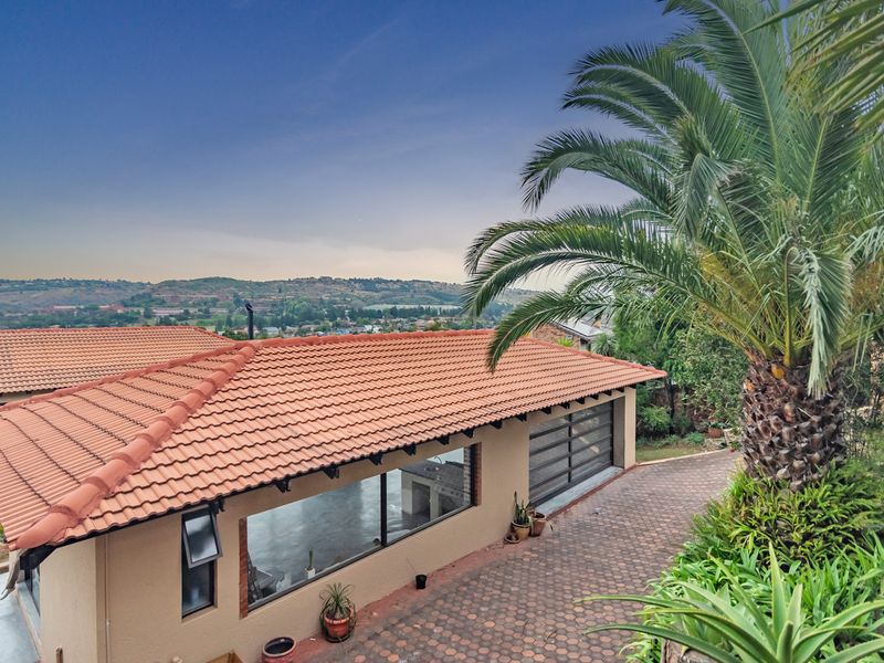 Elevated rear view of the property featuring a terracotta tiled roof, paved driveway, and expansive views of the surrounding landscape.