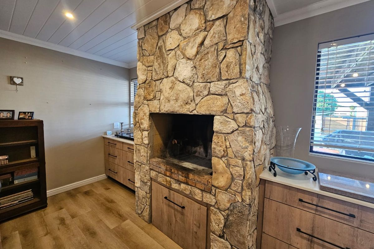 A cozy living area featuring a prominent stone fireplace, modern wood-look cabinetry, laminate flooring, and a clean tongue and groove ceiling finish.