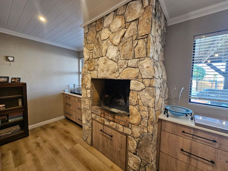 A cozy living area featuring a prominent stone fireplace, modern wood-look cabinetry, laminate flooring, and a clean tongue and groove ceiling finish.
