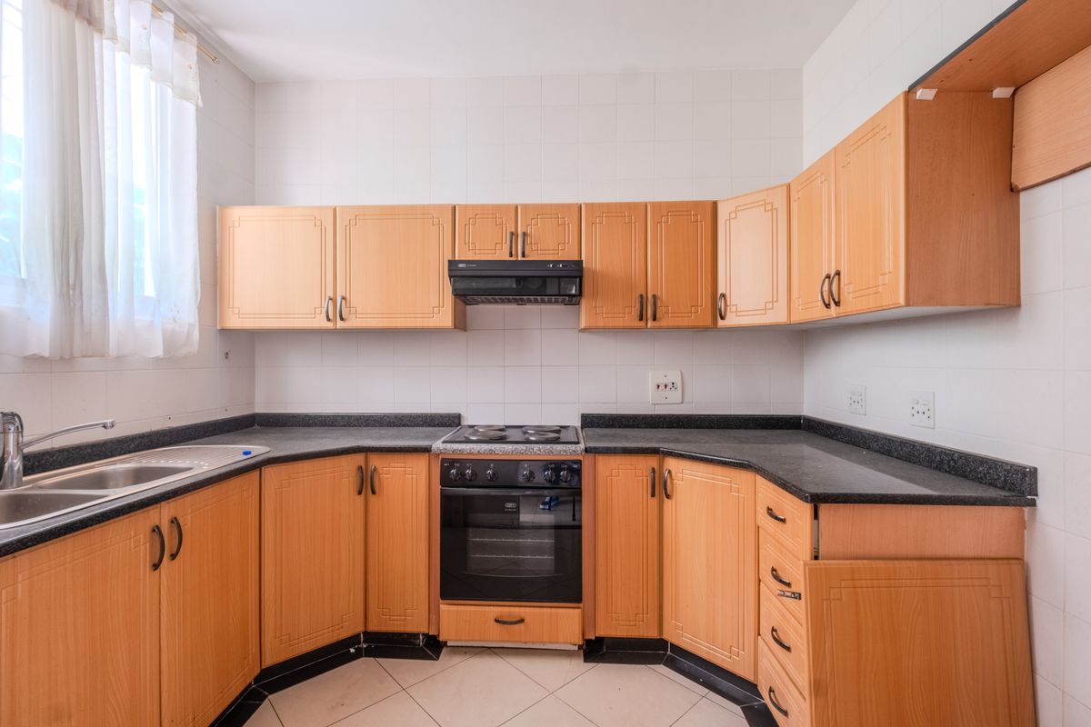 A functional kitchen featuring laminate cabinetry, granite countertops, a built-in oven with hob, and a stainless steel sink with tiled backsplash.