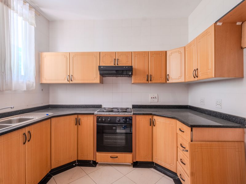 A functional kitchen featuring laminate cabinetry, granite countertops, a built-in oven with hob, and a stainless steel sink with tiled backsplash.