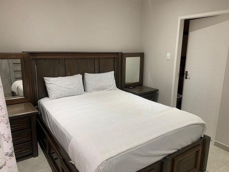A well-maintained bedroom featuring neutral wall tones, tiled flooring, and a standard internal door leading to an adjacent space.