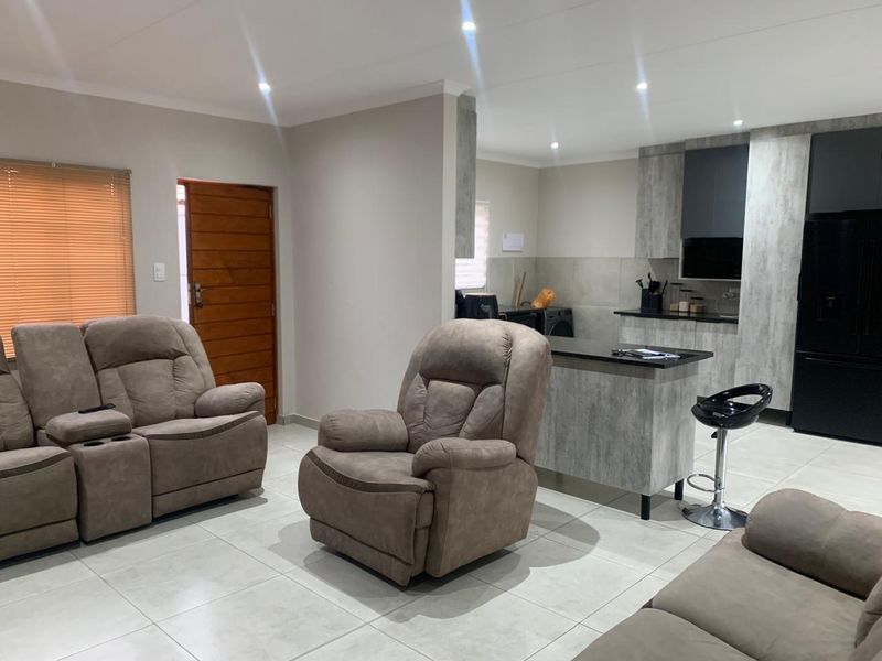 Modern open-plan living area featuring tiled floors, recessed lighting, and a contemporary kitchen with stone countertops and sleek cabinetry.