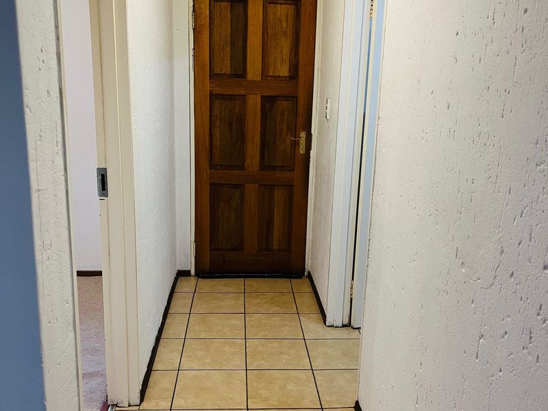 A functional hallway featuring tiled flooring and a traditional wooden door, connecting multiple rooms within the apartment.