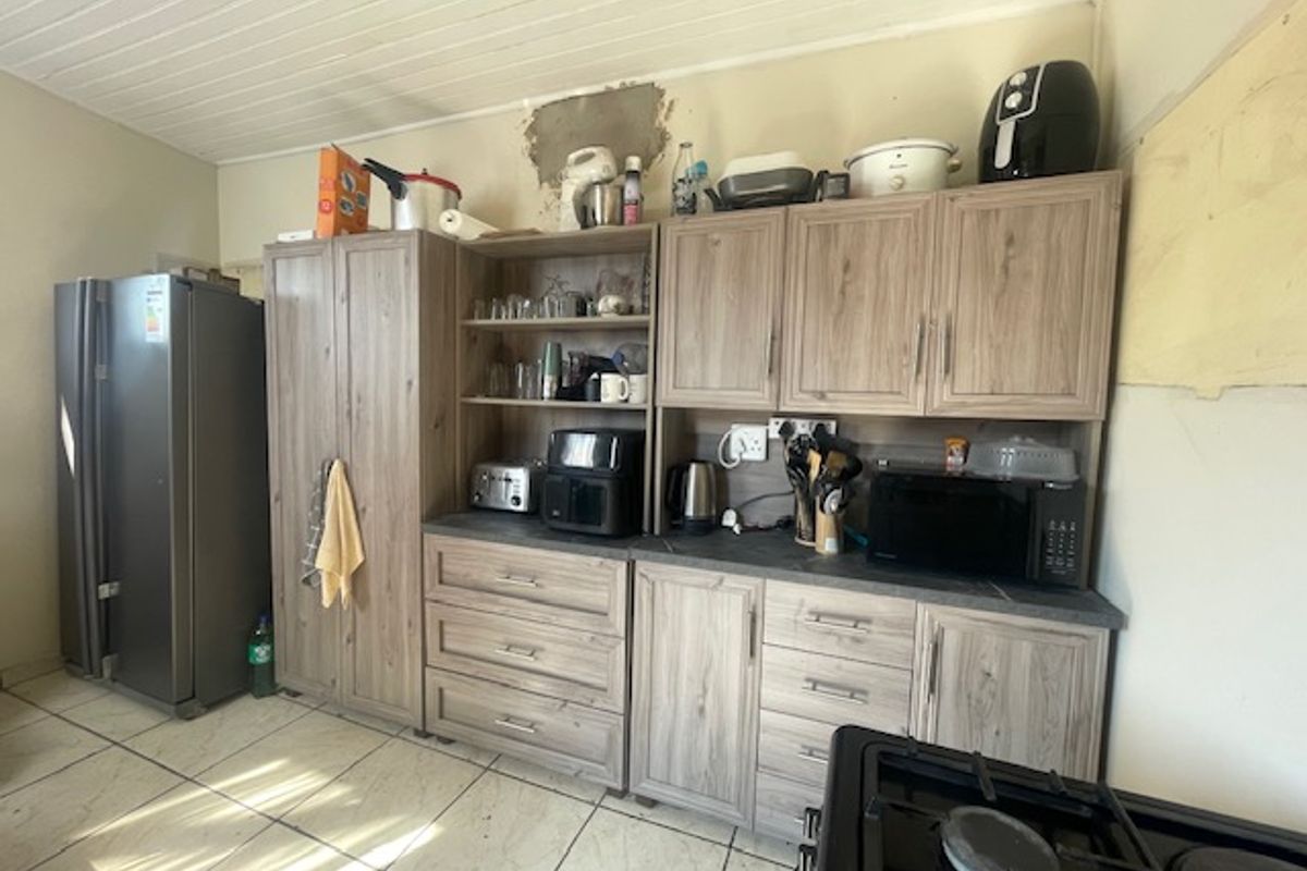 Kitchen area featuring wood-look cabinetry, tiled flooring, and tongue and groove ceiling, currently requiring wall repairs and finishing.