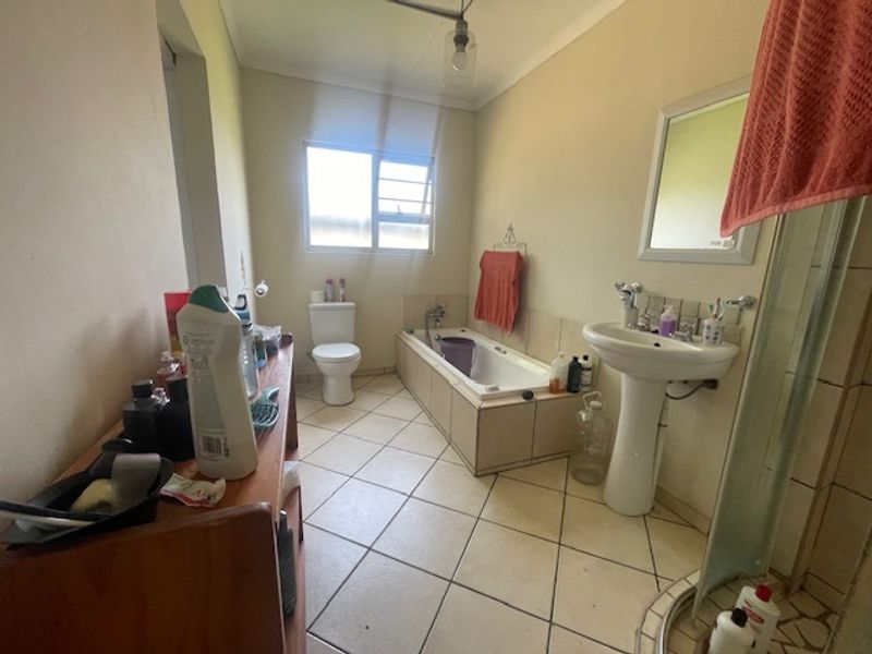 A functional bathroom featuring a pedestal basin, built-in bathtub, separate shower enclosure, and tiled flooring.