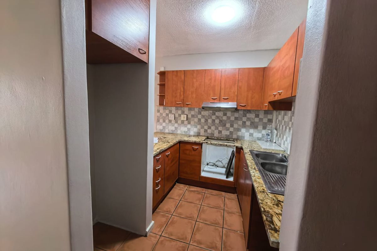 Compact kitchen featuring laminate cabinetry, granite countertops, a double stainless steel sink, and a tiled backsplash. The space is currently missing a built-in oven.
