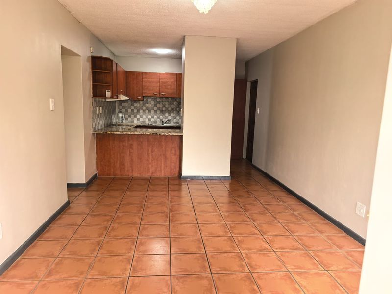 Open plan living area featuring a compact kitchen with built-in cabinetry, granite countertops, and tiled flooring throughout.