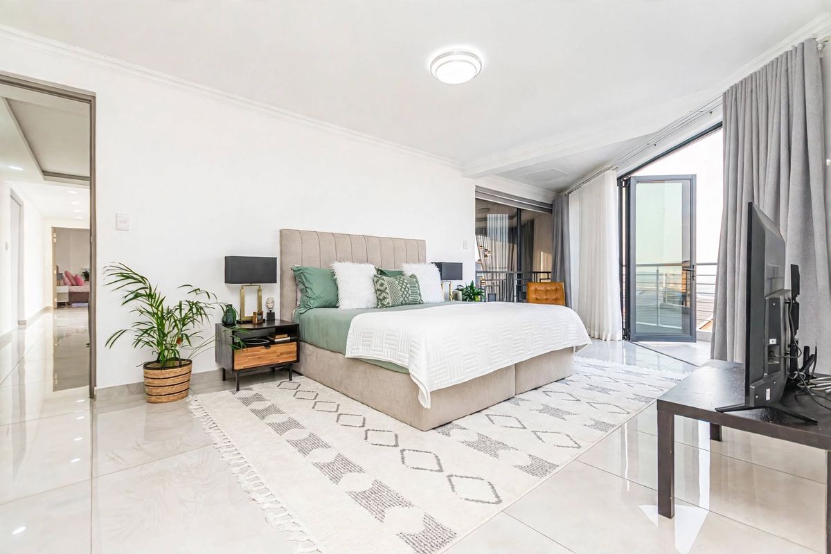 Spacious bedroom featuring polished tiled flooring, neutral walls, and large sliding glass doors providing access to an outdoor balcony area.
