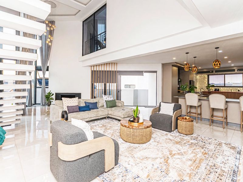 Spacious open-plan living area featuring a modern kitchen with island, double-volume ceilings, and a striking floating staircase.