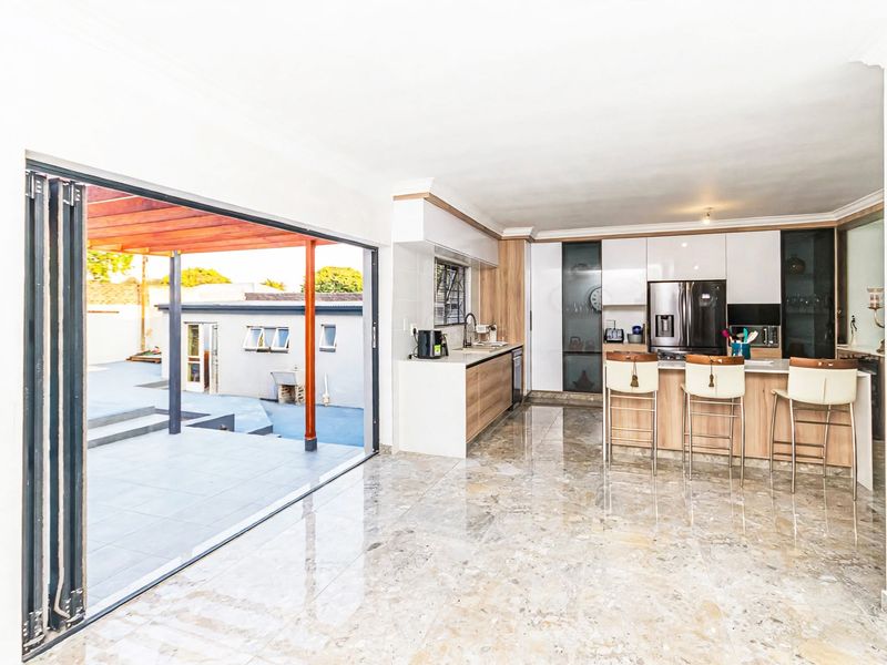 Modern open-plan kitchen featuring a central island, sleek cabinetry, and seamless indoor-outdoor flow through large bi-fold doors to the patio area.