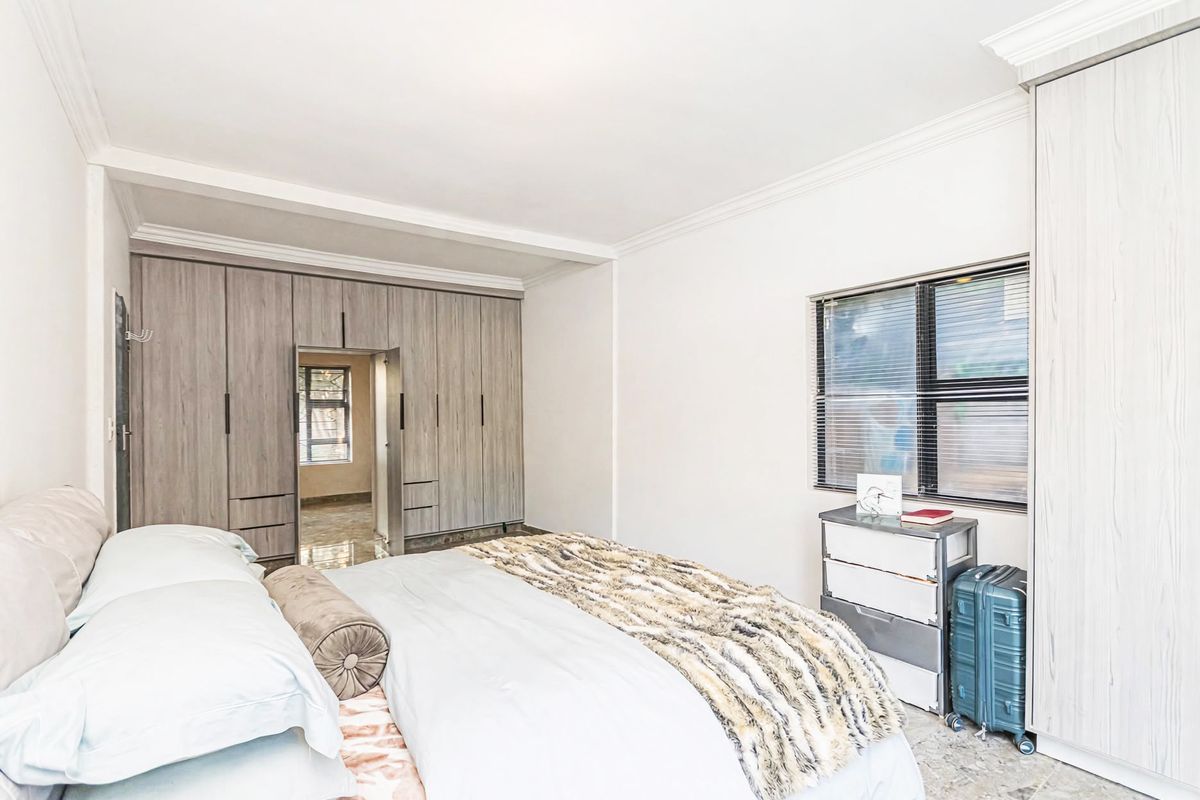 A well-lit bedroom featuring neutral walls, tiled flooring, and extensive built-in cabinetry providing ample storage space.