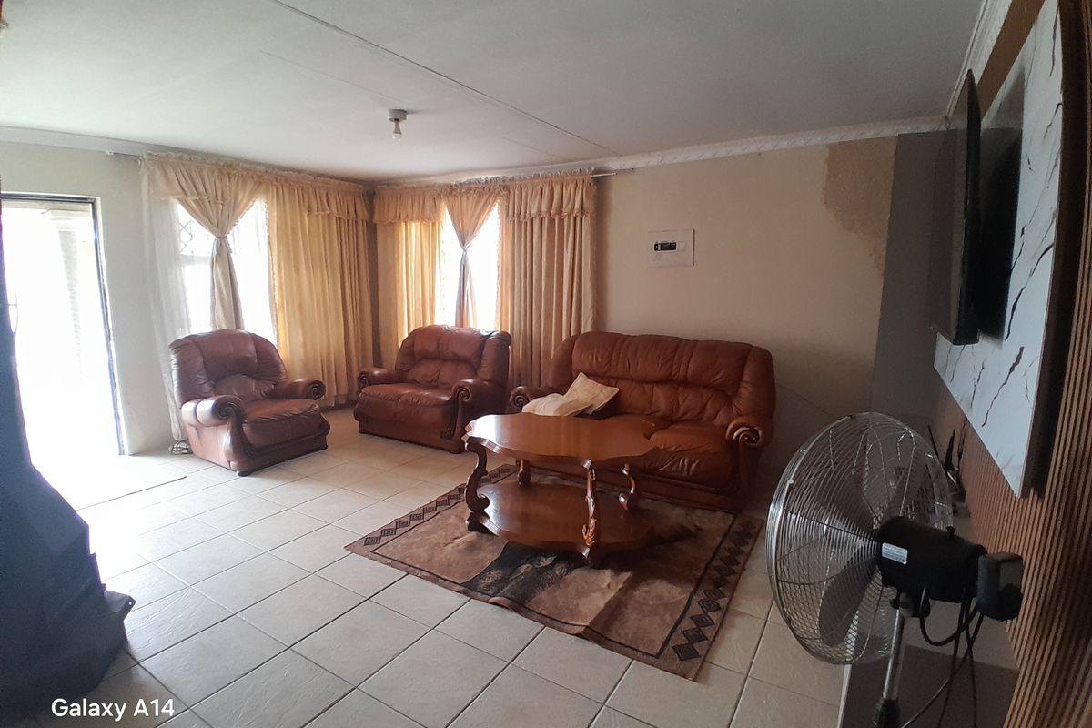 A living room featuring tiled flooring and a sliding door, showing visible signs of water damage on the wall requiring repair.