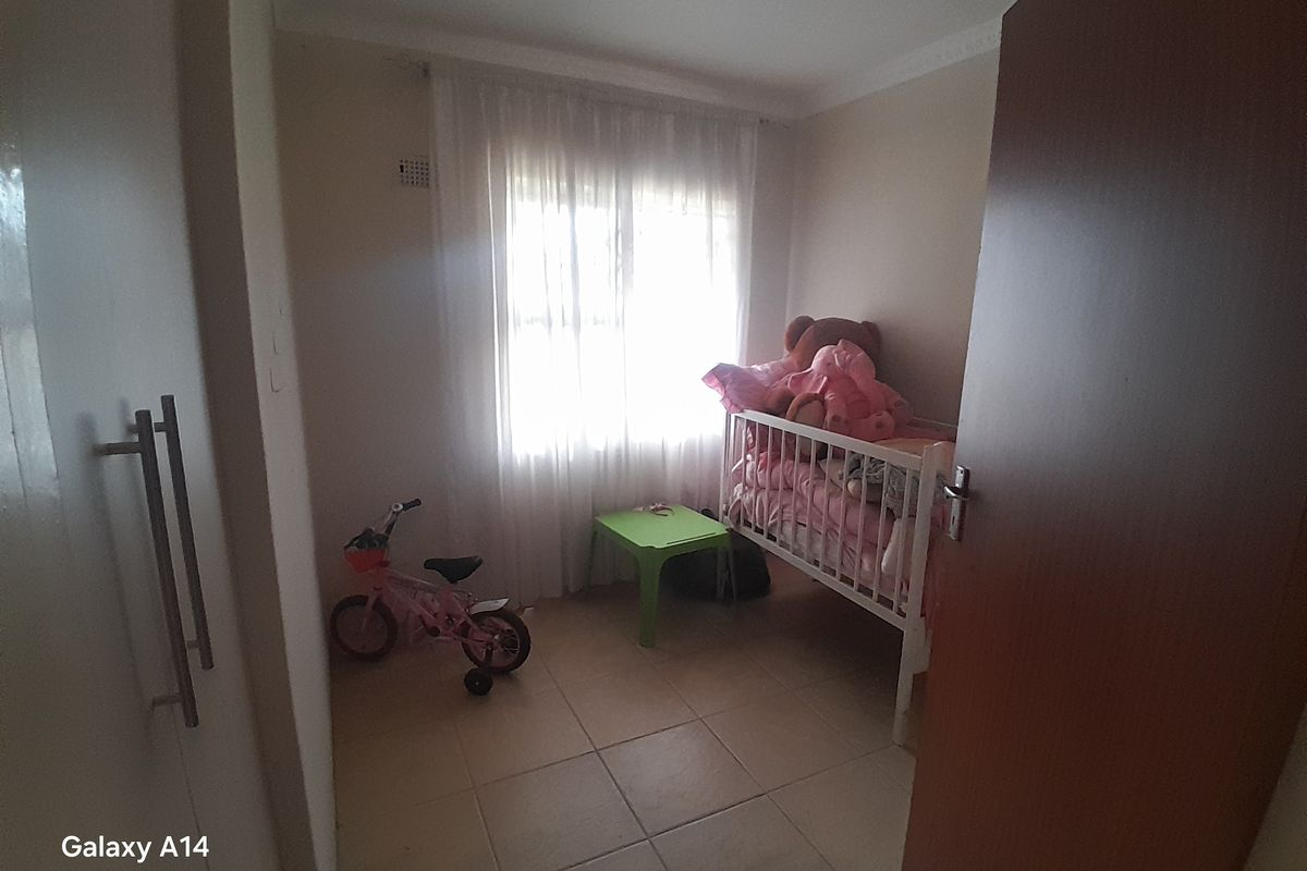 A compact bedroom featuring tiled flooring, built-in cupboards, and a window with curtains, providing a functional space for a child's room.