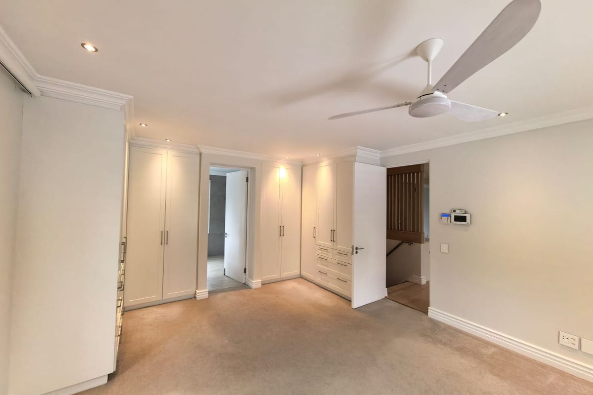 Spacious bedroom featuring extensive built-in cabinetry, neutral carpeting, recessed lighting, and a modern ceiling fan.