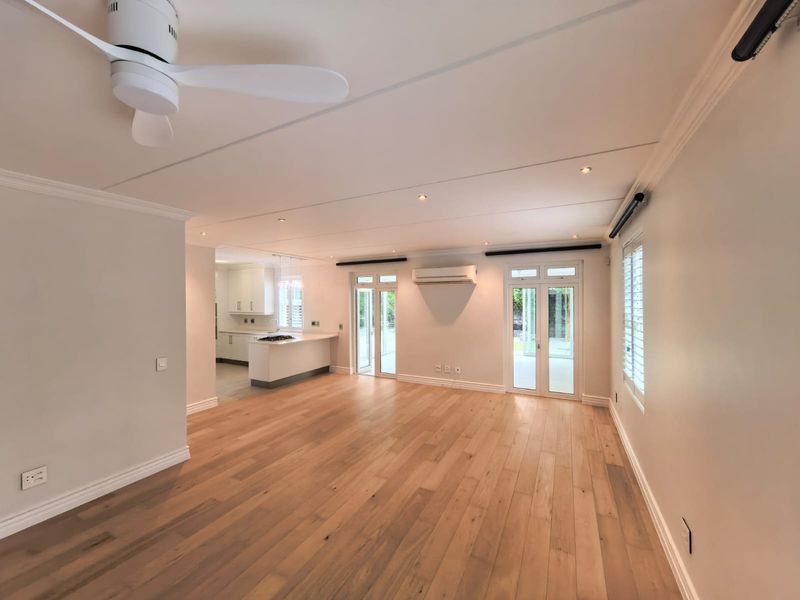 Spacious open-plan living area featuring hardwood flooring, recessed lighting, a ceiling fan, and seamless access to the outdoors through double french doors.