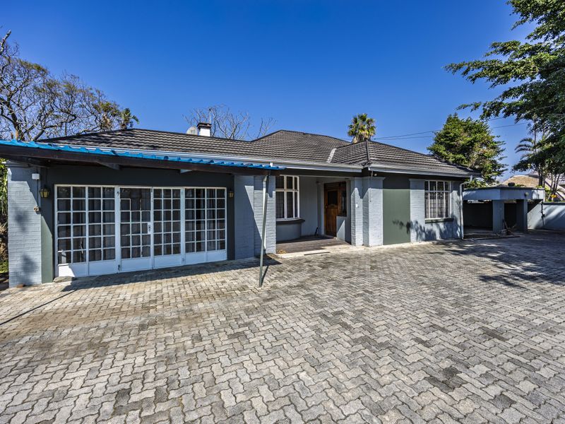 Front exterior view of a single-story house featuring a paved driveway, covered entrance patio, and a tiled roof.