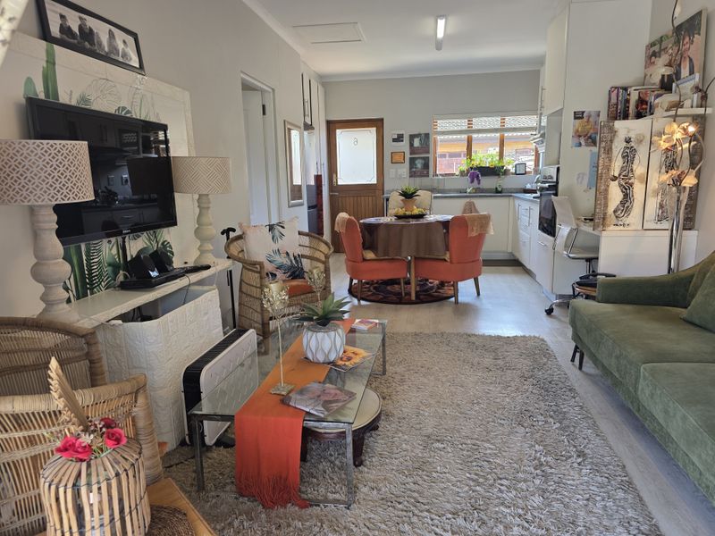 An open-plan living and kitchen area featuring laminate flooring, built-in cabinetry, and a functional layout suitable for comfortable retirement living.