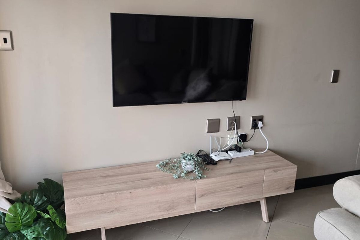 A living room area featuring neutral wall tones, crown molding, and tiled flooring, providing a clean and functional space.