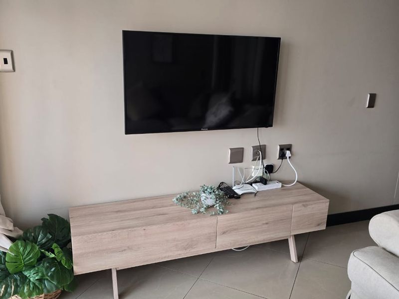 A living room area featuring neutral wall tones, crown molding, and tiled flooring, providing a clean and functional space.