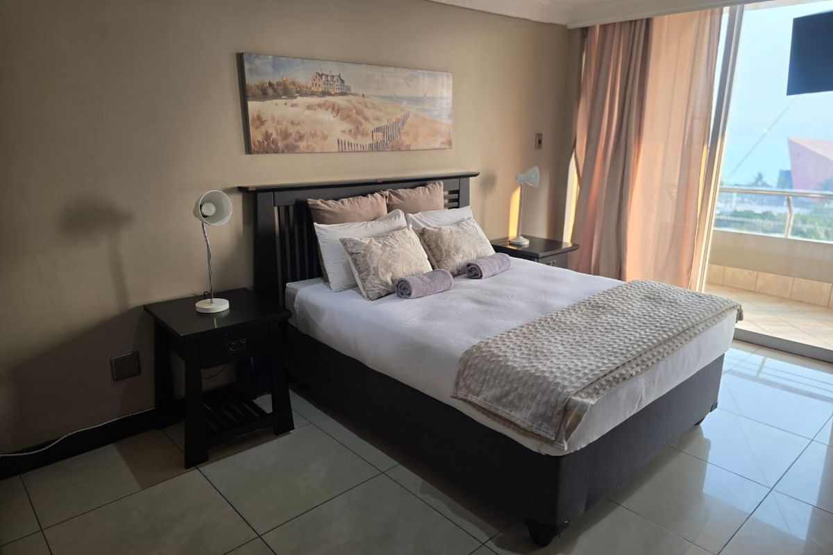 A well-maintained bedroom featuring tiled flooring, crown molding, and a sliding glass door providing access to a balcony with exterior views.