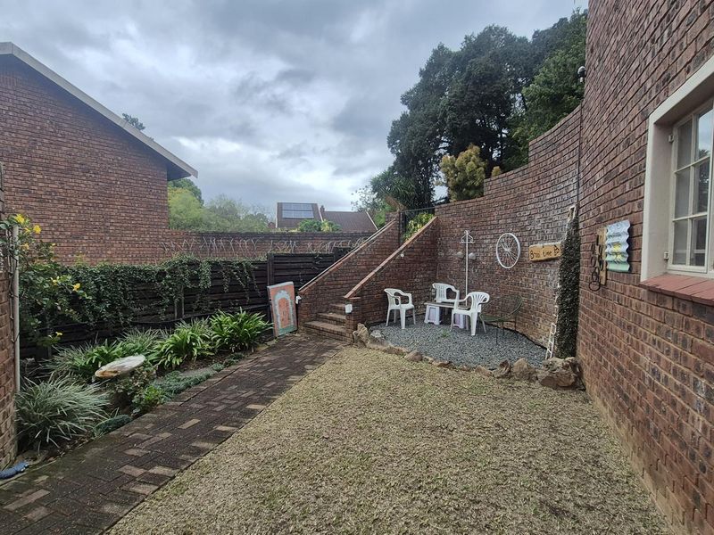 A private rear courtyard featuring a paved walkway, gravel garden area, and brick boundary walls with an external staircase.