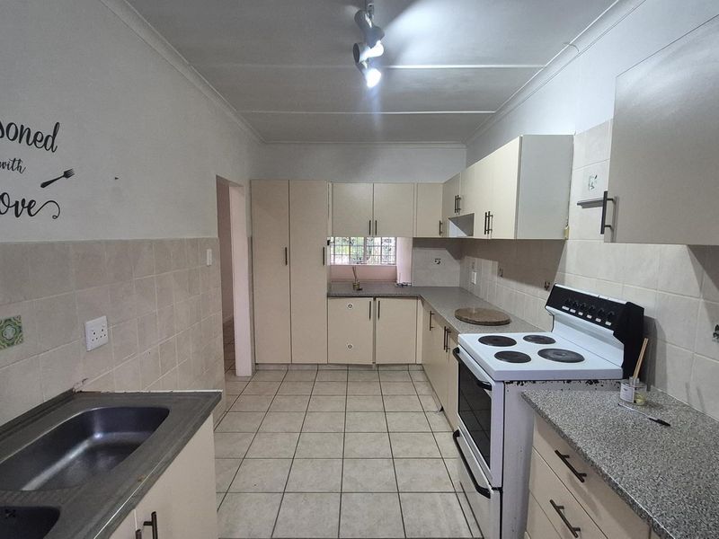 Functional kitchen featuring ample built-in cabinetry, laminate countertops, tiled backsplash, and a freestanding stove, offering a practical layout for daily meal preparation.