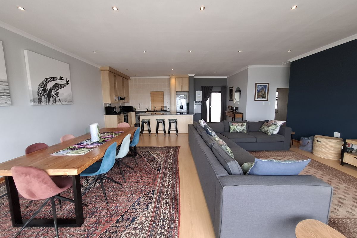 Spacious open-plan living and dining area featuring laminate flooring, recessed lighting, and a functional kitchen with a central island and built-in appliances.