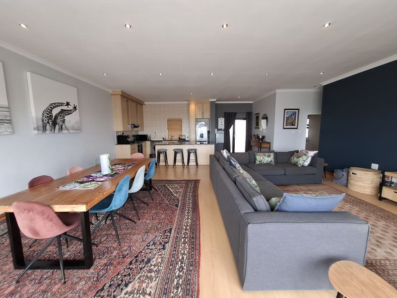 Spacious open-plan living and dining area featuring laminate flooring, recessed lighting, and a functional kitchen with a central island and built-in appliances.