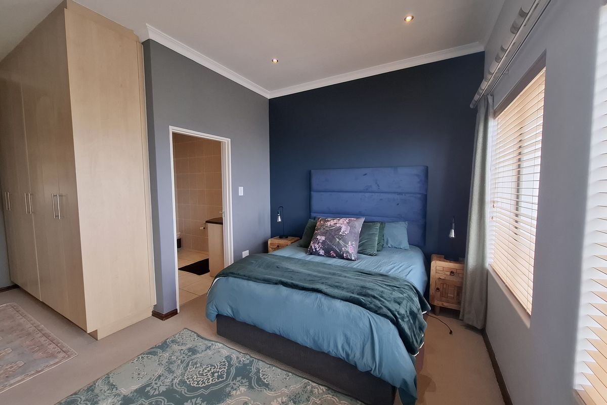 A well-maintained bedroom featuring built-in cupboards, recessed lighting, venetian blinds, and direct access to an en-suite bathroom.