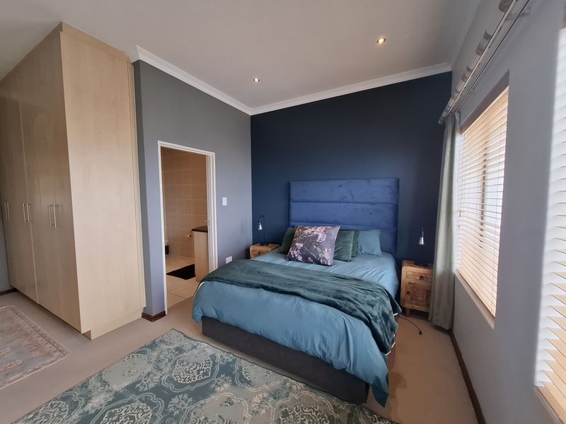 A well-maintained bedroom featuring built-in cupboards, recessed lighting, venetian blinds, and direct access to an en-suite bathroom.